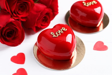 Photo of St. Valentine's Day. Delicious heart shaped cakes and beautiful roses on white wooden table, closeup