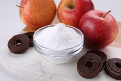 Photo of Sweet fructose powder, fruit leather rolls and apples on white table, closeup
