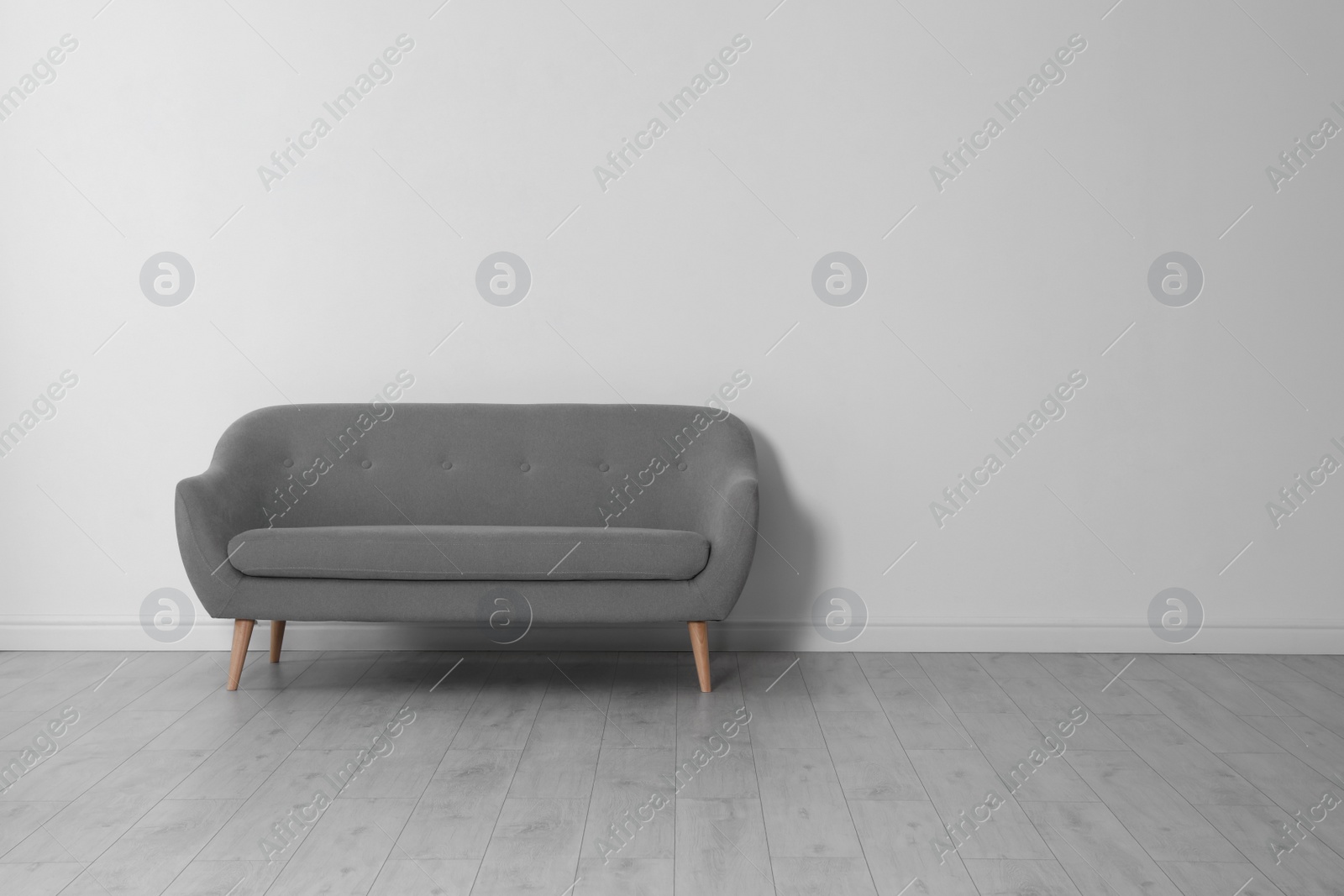 Photo of Room interior with comfortable sofa near white wall. Space for text