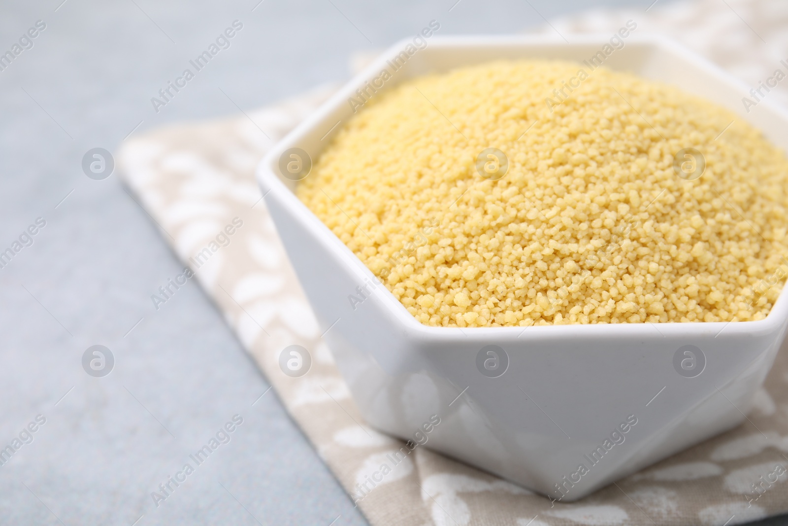 Photo of Raw couscous in bowl on gray table, closeup. Space for text