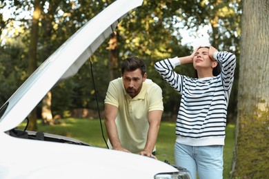 Photo of Stressed couple near broken car outdoors on summer day