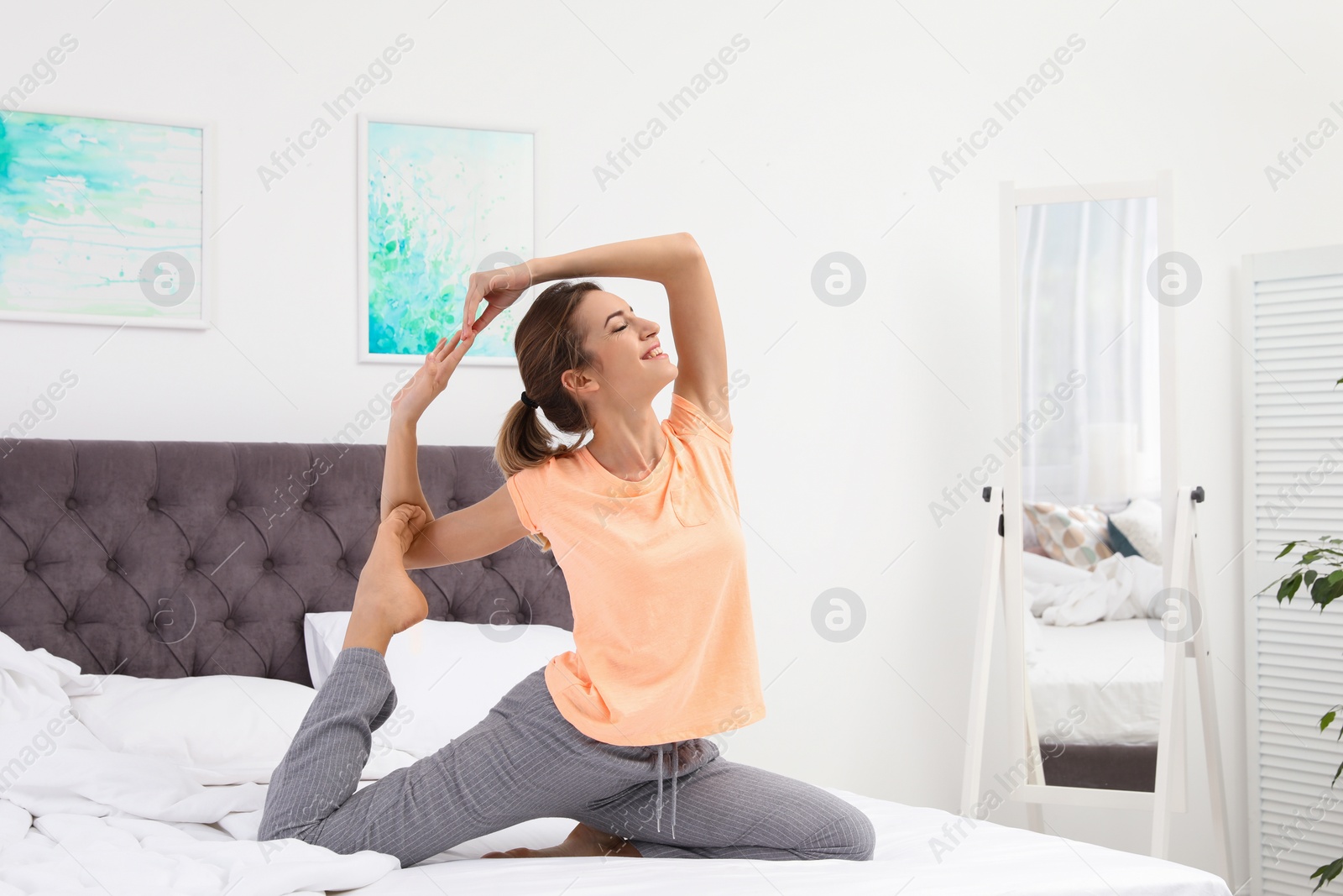 Photo of Young beautiful woman doing exercise on bed at home. Morning fitness