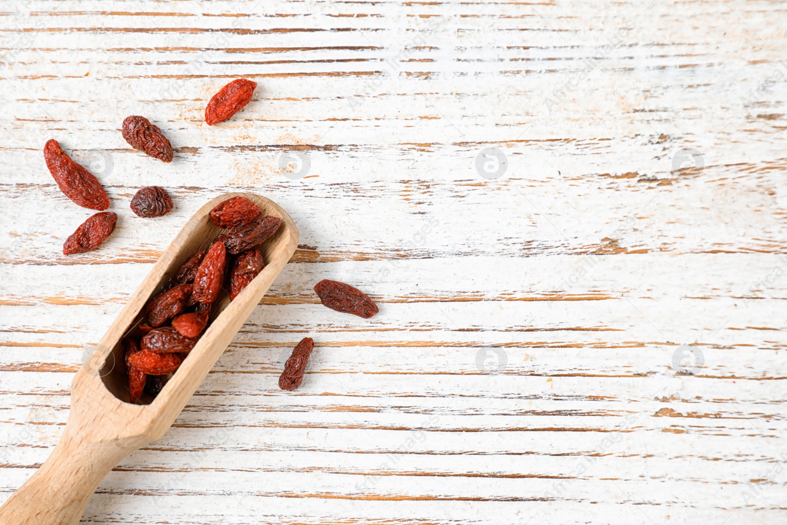 Photo of Dried goji berries on white wooden table, top view. Space for text