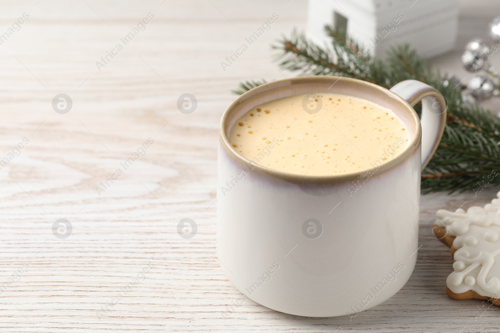 Photo of Cup of delicious eggnog on wooden table, space for text