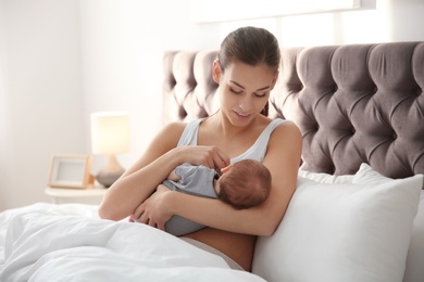 Photo of Young woman breastfeeding her baby in bedroom