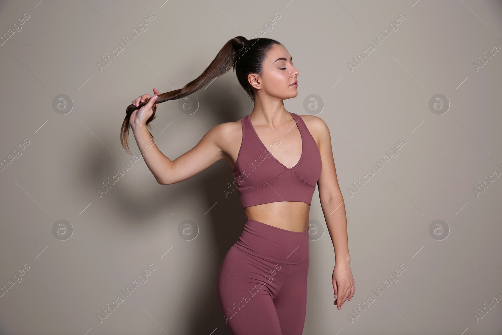 Photo of Young woman in sportswear on grey background