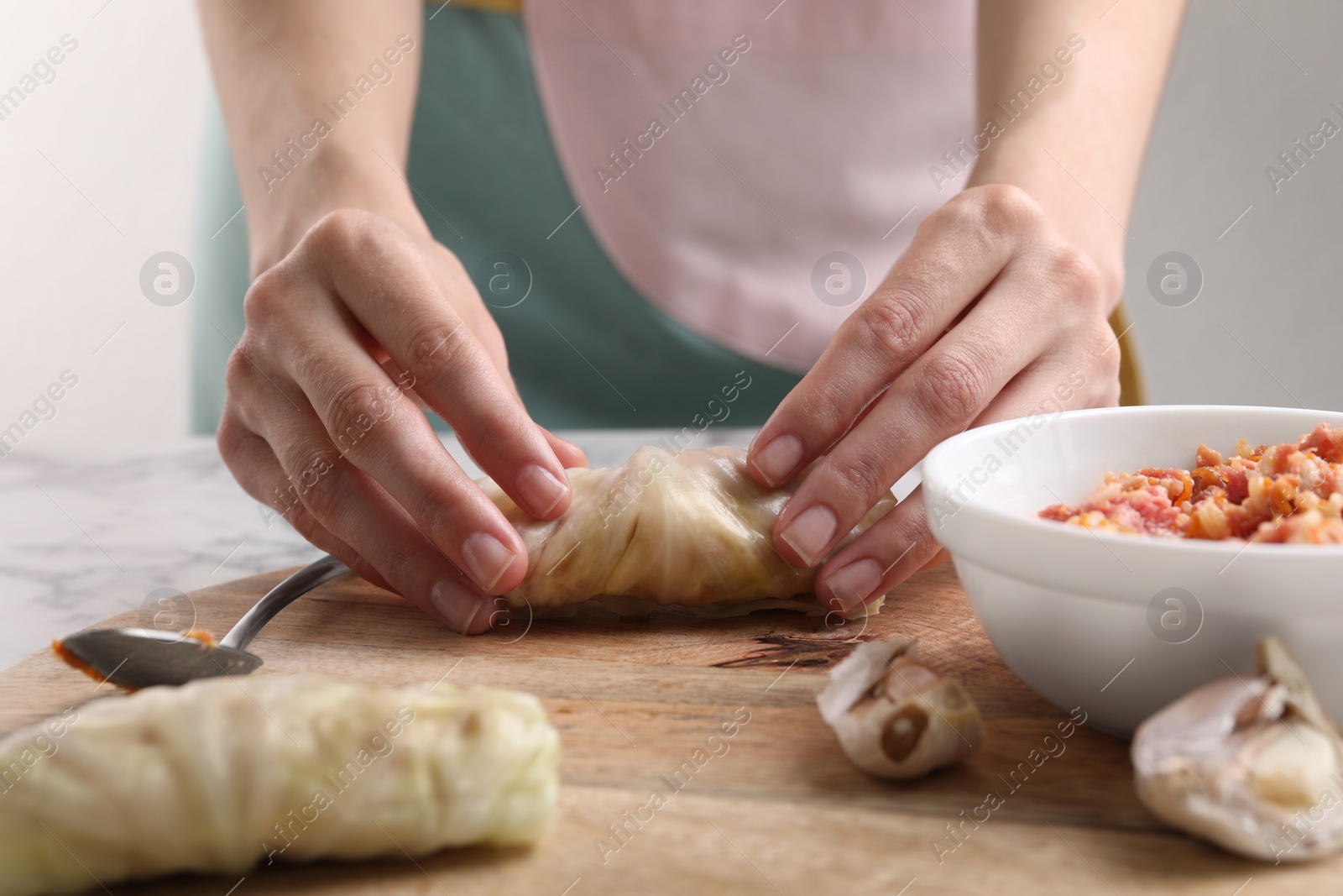 Photo of Woman preparing stuffed cabbage roll at table, closeup