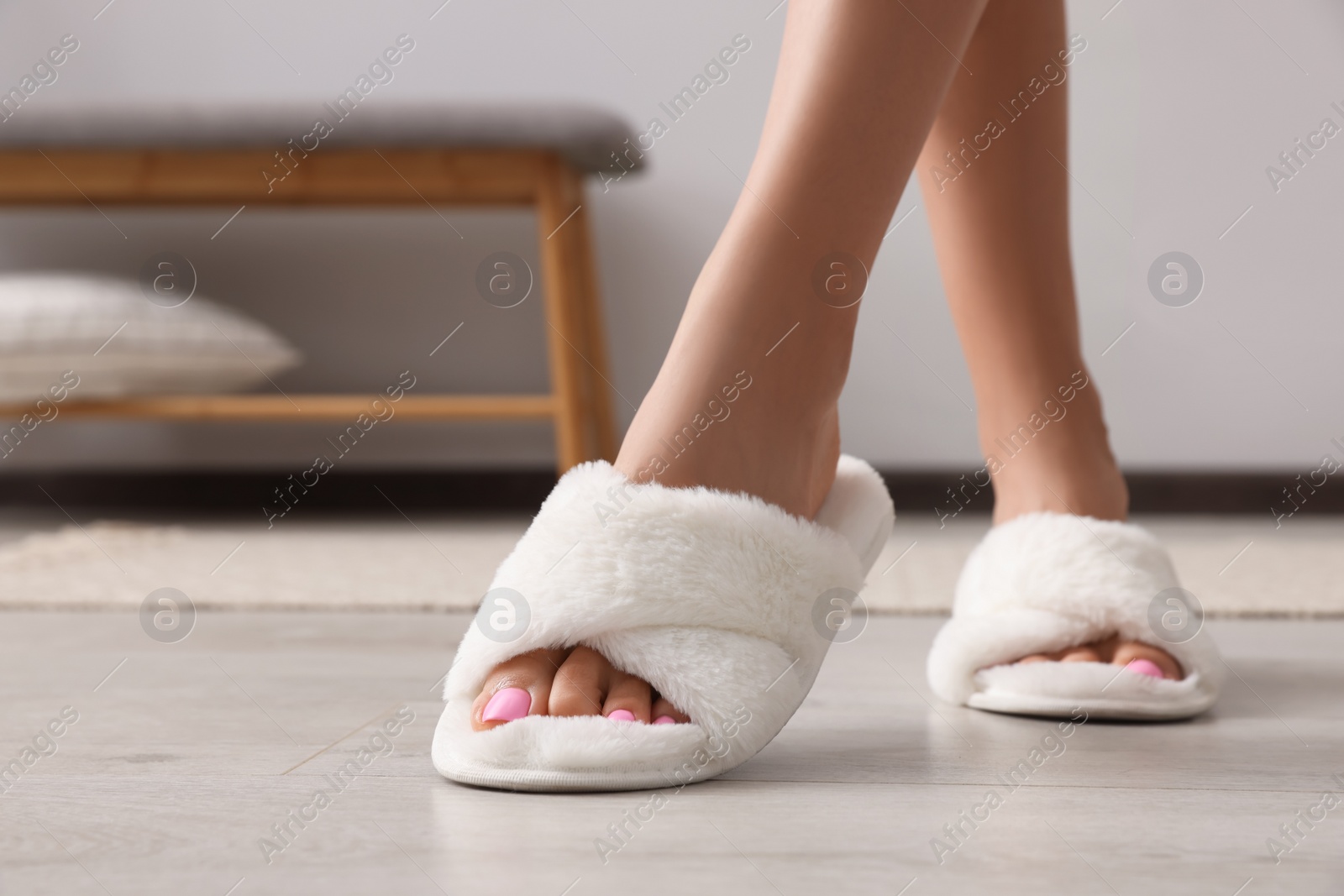 Photo of Woman wearing white soft slippers indoors, closeup. Space for text