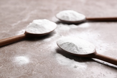 Spoons with baking soda on grey background