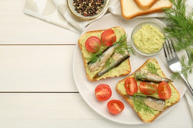 Photo of Delicious sandwiches with sprats, tomatoes, dill and avocado puree served on white wooden table, flat lay. Space for text