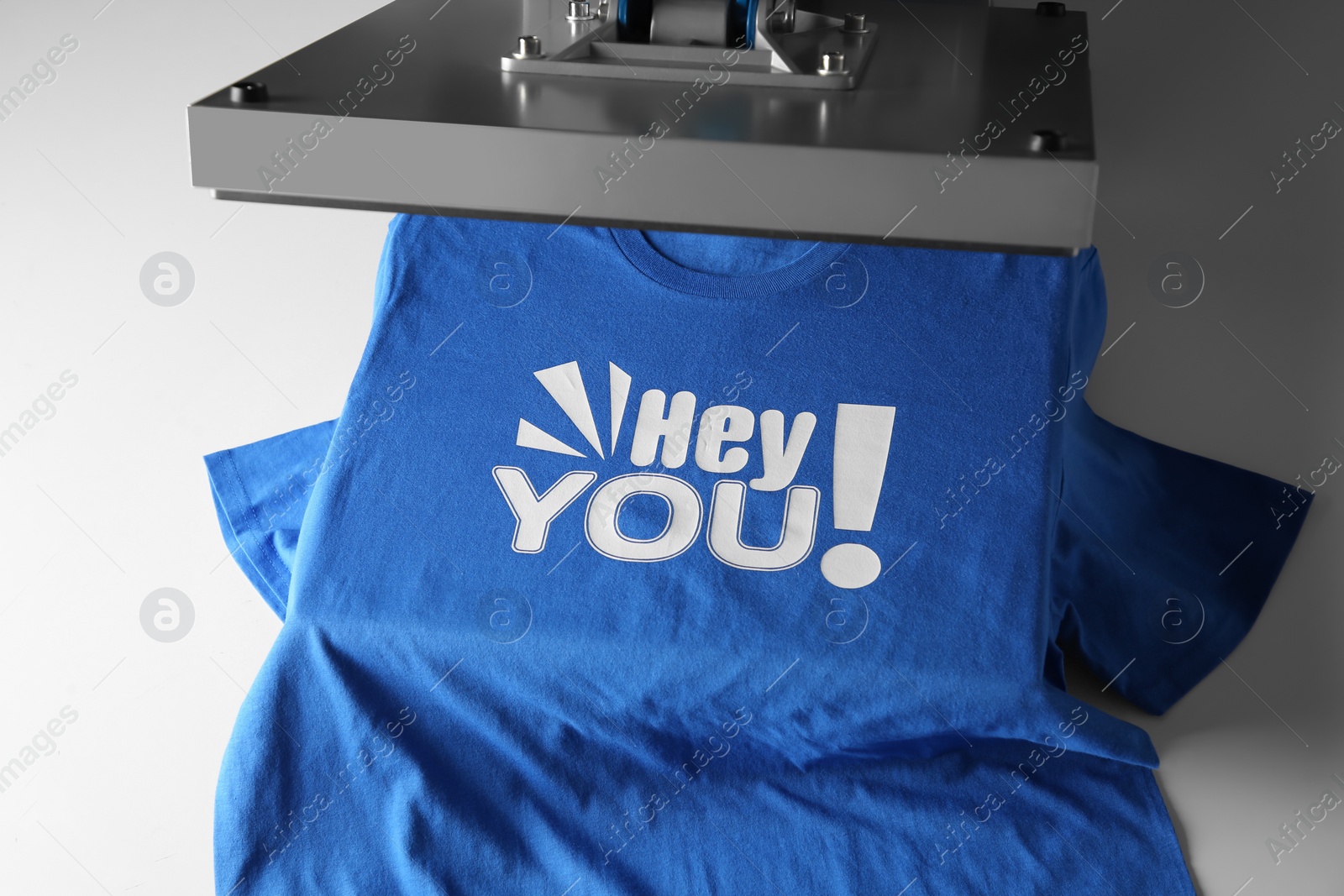 Photo of Printing logo. Heat press with blue t-shirt on white table