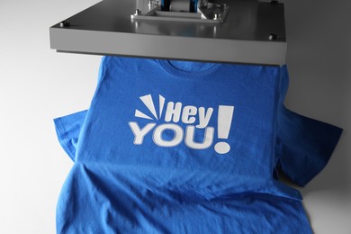 Photo of Printing logo. Heat press with blue t-shirt on white table