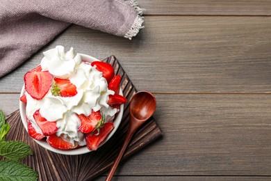 Photo of Delicious strawberries with whipped cream served on wooden table, flat lay. Space for text