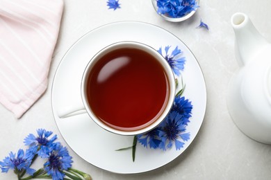 Photo of Composition with tea and cornflowers on light table, flat lay