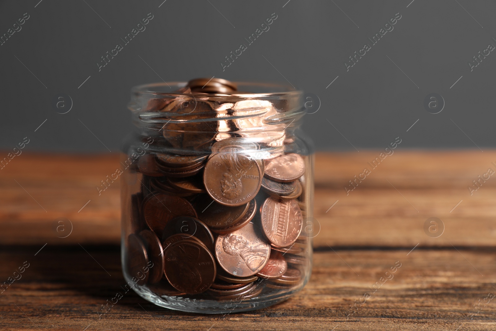 Photo of Donation jar with coins on wooden table against grey background