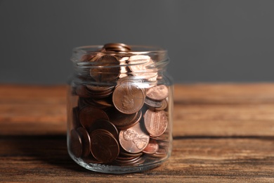 Photo of Donation jar with coins on wooden table against grey background