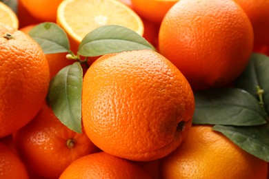 Photo of Fresh ripe oranges with green leaves as background, closeup