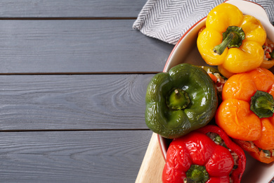 Photo of Tasty stuffed bell peppers in baking dish on grey wooden table, top view. Space for text