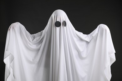 Creepy ghost. Person covered with white sheet on black background