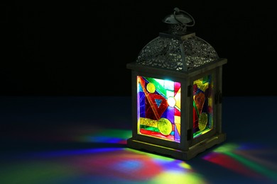 Decorative Arabic lantern on table against dark background. Space for text