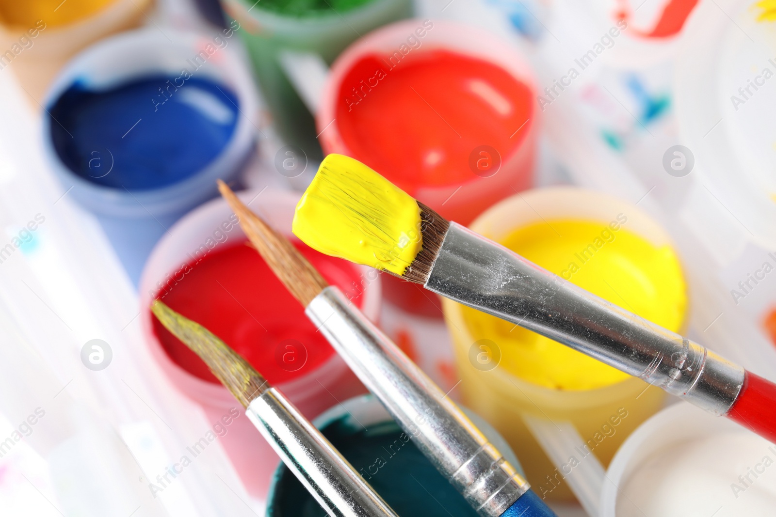 Photo of Jars with color paints and brushes on table, closeup