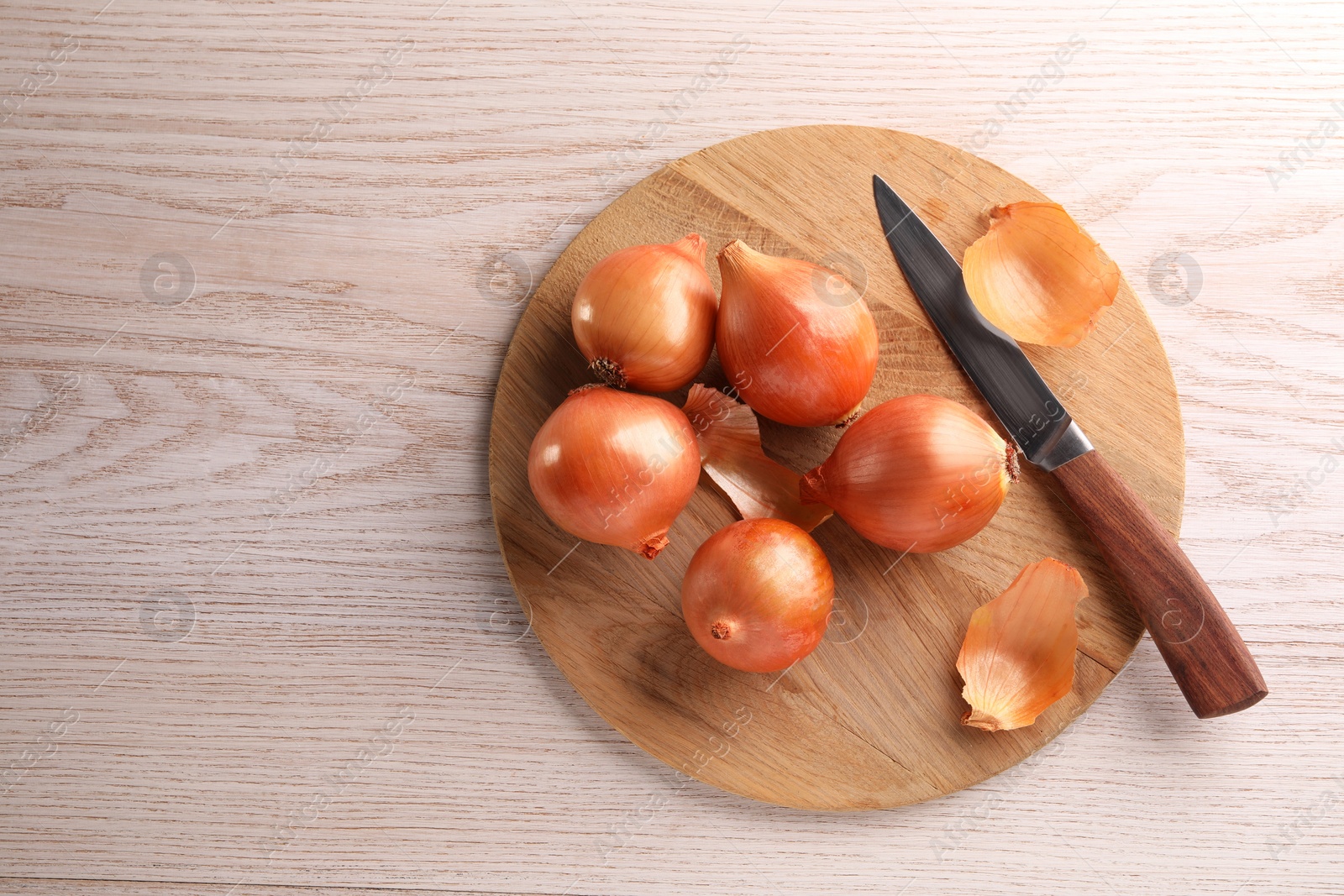 Photo of Tray with ripe onions and knife on wooden table, top view. Space for text