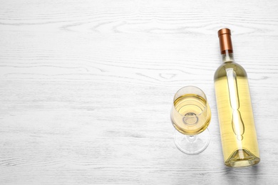 Photo of Glass and bottle with white wine on wooden background, view from above. Space for text