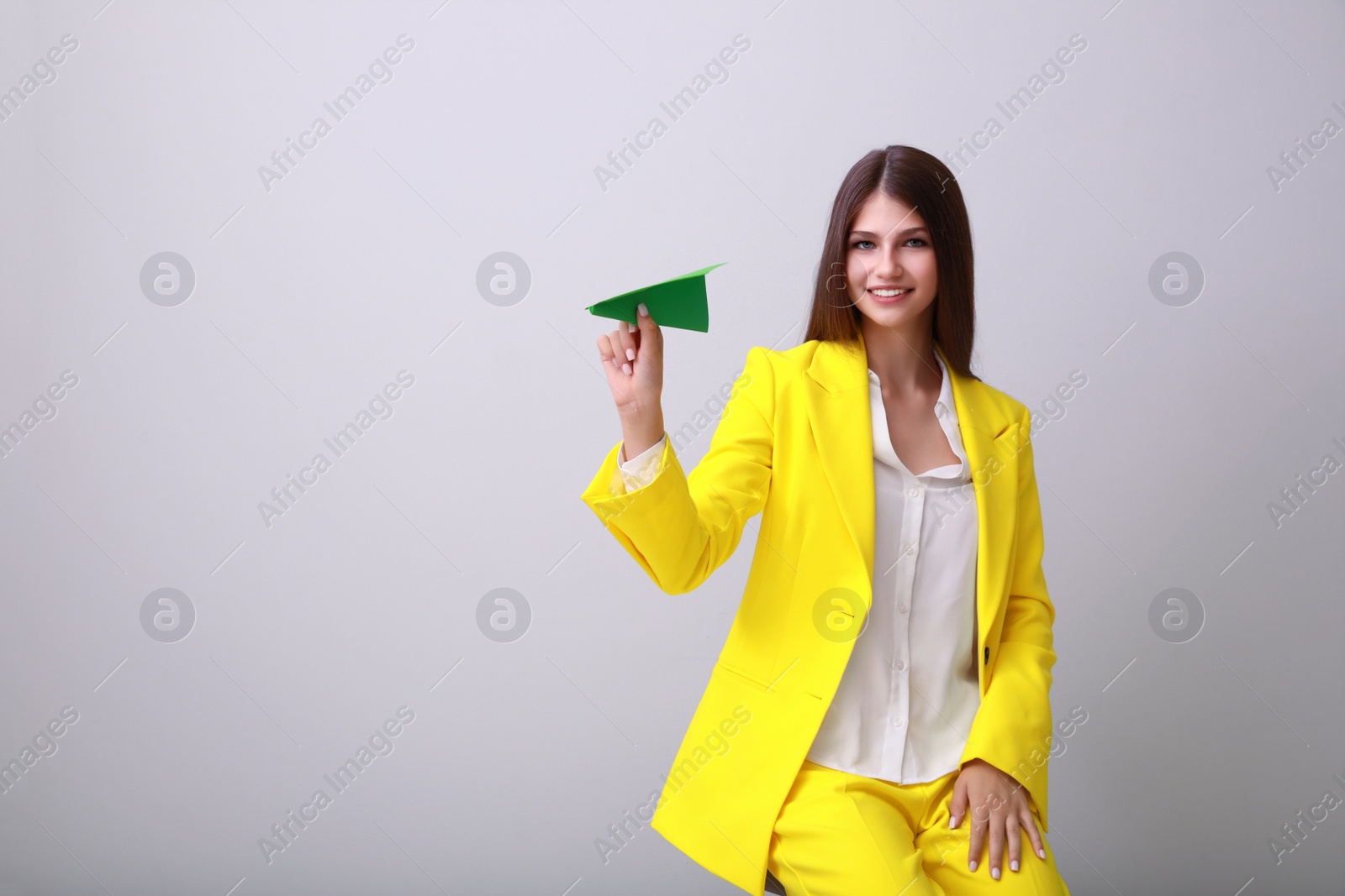 Photo of Beautiful teenage girl with paper plane on grey background. Space for text