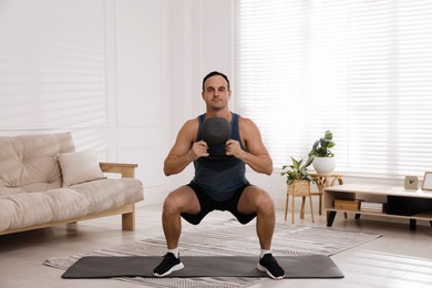 Photo of Muscular man training with kettlebell at home