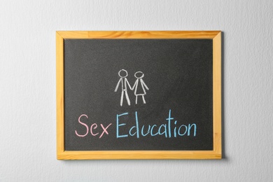 Small blackboard with written phrase "SEX EDUCATION" on white wall