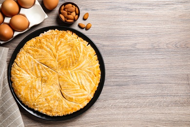Traditional galette des rois and ingredients on wooden table, flat lay. Space for text
