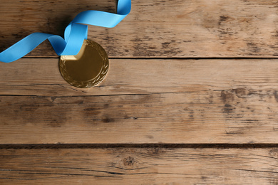 Medal with light blue ribbon on wooden background, flat lay. Space for design