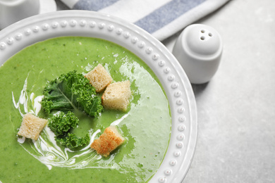 Photo of Tasty kale soup with croutons on grey table, flat lay