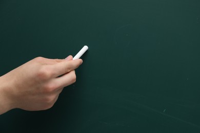 Teacher writing with chalk on green chalkboard, closeup. Space for text