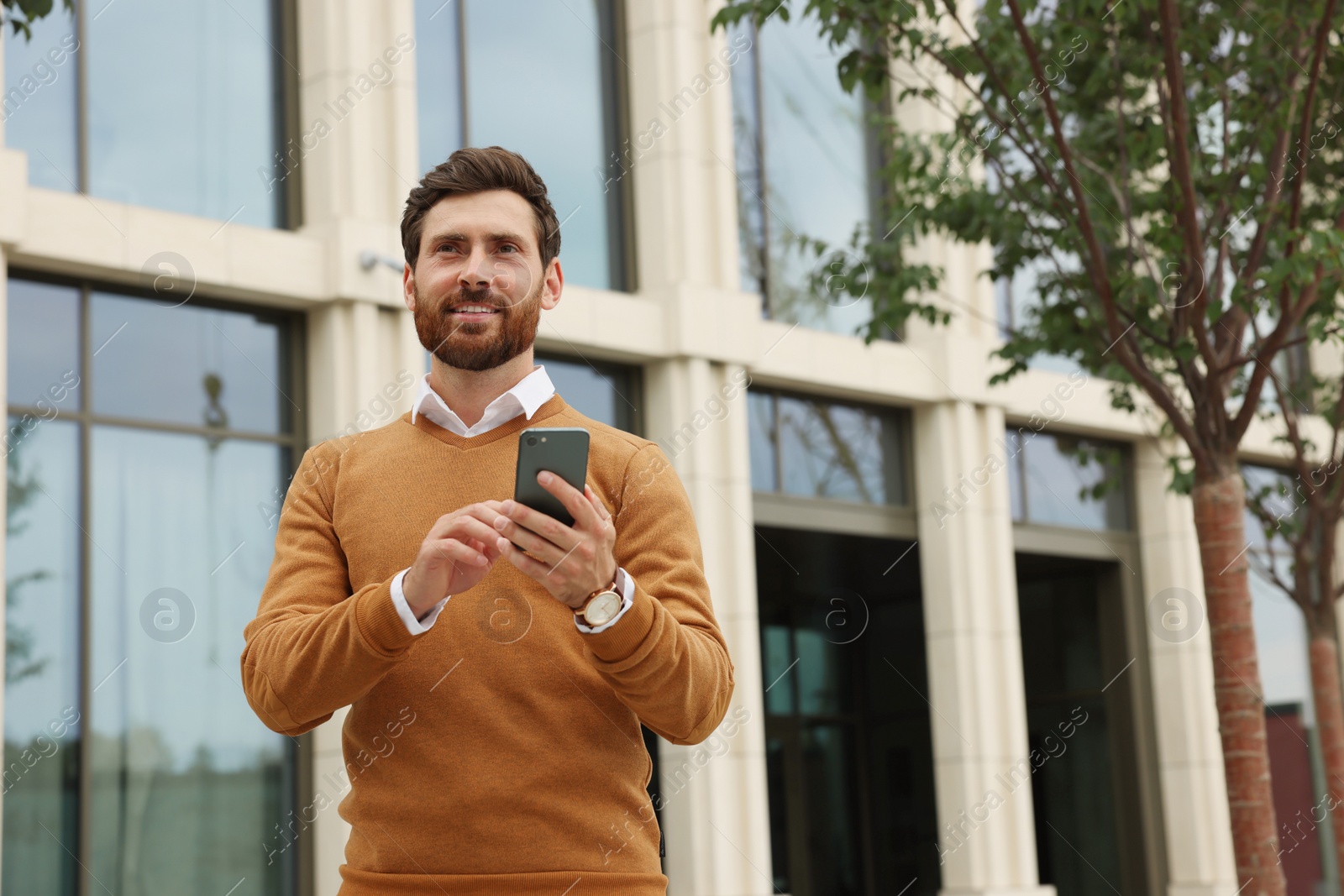 Photo of Handsome man with smartphone on city street, space for text