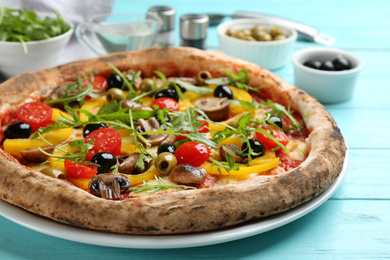 Photo of Delicious vegetable pizza on light blue wooden table, closeup