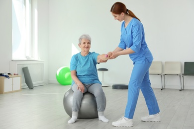 Professional physiotherapist working with elderly patient in rehabilitation center