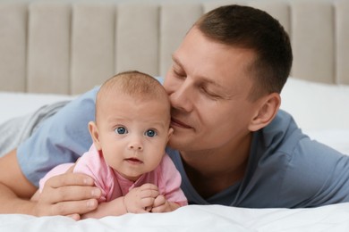 Photo of Happy father with his cute baby on bed at home