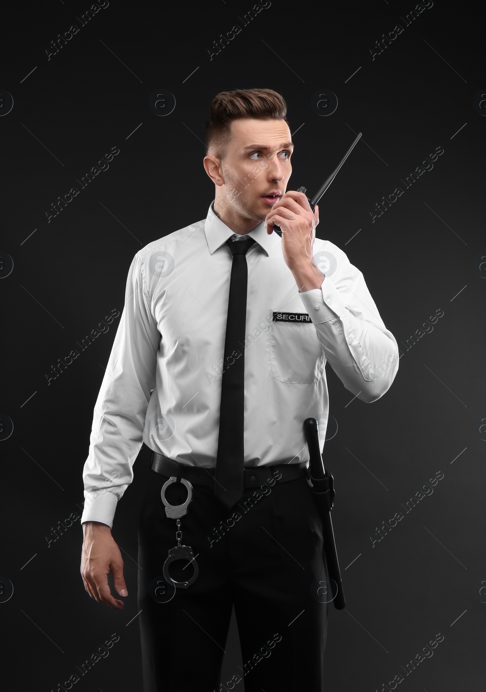 Photo of Male security guard using portable radio transmitter on dark background