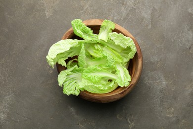 Fresh Chinese cabbage leaves in bowl on gray textured table, top view