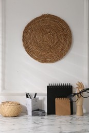 Stylish office workplace. Decor elements, glasses and stationery on marble table near white wall