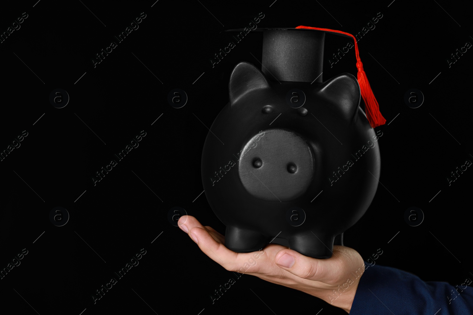 Photo of Man holding piggy bank and graduation cap against black background, closeup with space for text. Scholarship concept