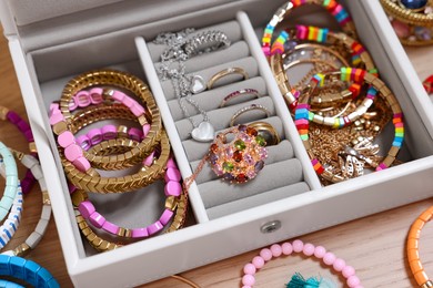 Photo of Jewelry box with stylish bracelets and other accessories on wooden table, closeup