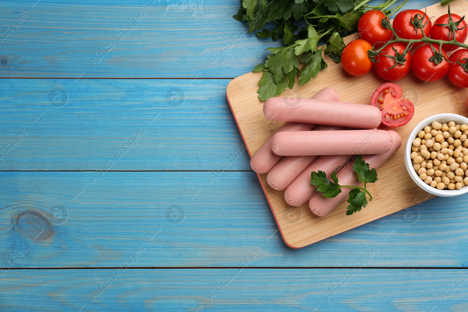 Photo of Fresh raw vegetarian sausages and vegetables on light blue wooden table, flat lay. Space for text