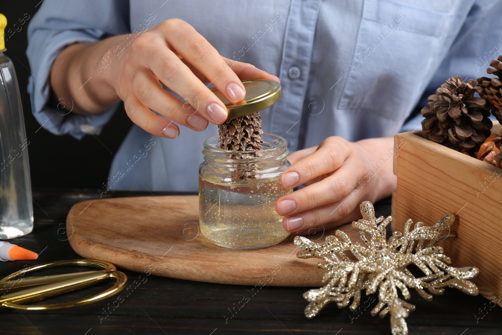 Photo of Woman making snow globe at black wooden table, closeup