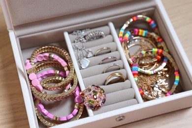 Photo of Jewelry box with stylish bracelets and other accessories on wooden table, closeup