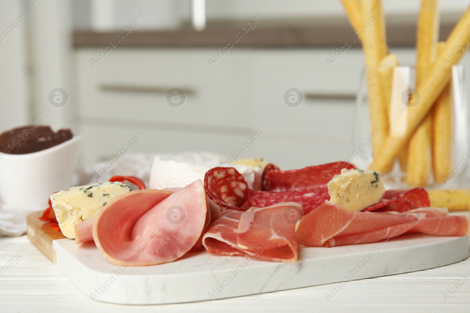 Photo of Tasty ham with other delicacies served on white wooden table, closeup