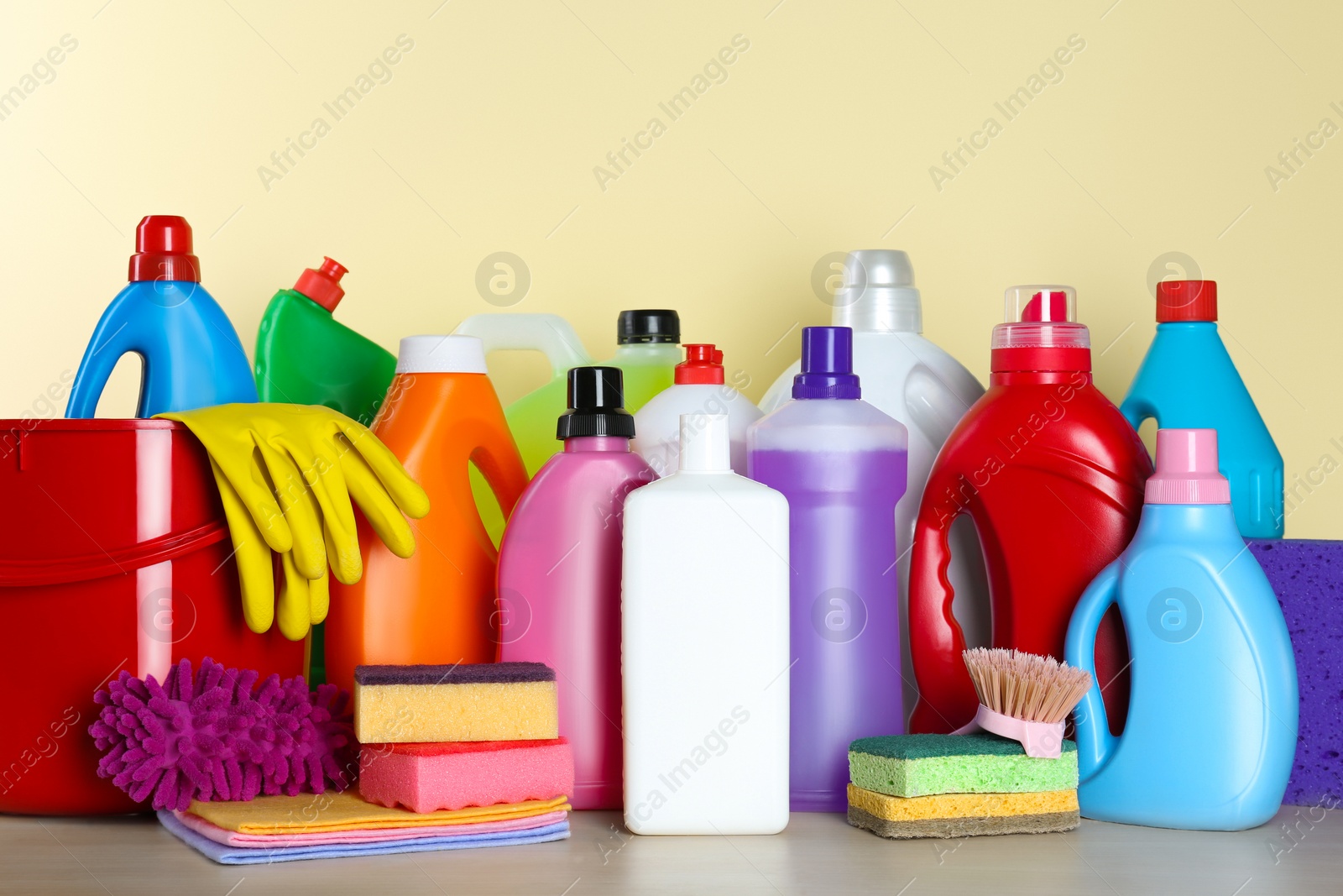 Photo of Different cleaning supplies and tools on table against beige