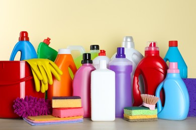 Photo of Different cleaning supplies and tools on table against beige