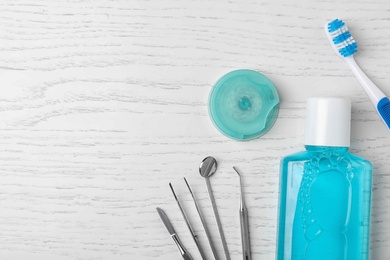 Flat lay composition with dentist tools and teeth care objects on wooden background. Space for text